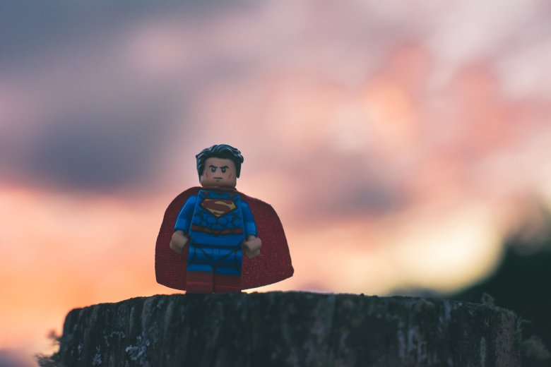 lego superman au sommet d'une montagne devant le couché du soleil